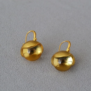 Detailed view of vintage gold-plated bud earrings with crystal glass globes on linen texture