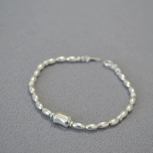 Detail shot of Baroque seed pearl necklace with a central irregular polished silver bead