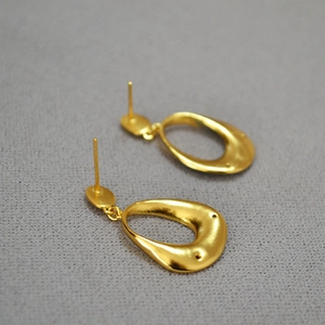 Detail of vintage gold plated brass earrings featuring blue enamel and flower patterns