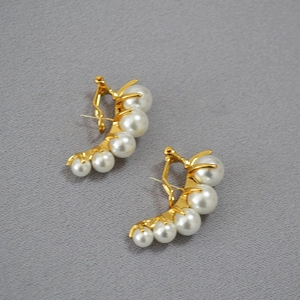Close-up of vintage gold curved earrings with five graduated white pearls in claw setting