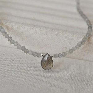 Close-up of beaded necklace with grey stones and a teardrop labradorite pendant
