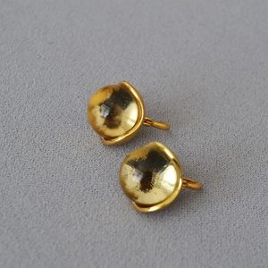 Macro detail of vintage brass floral earrings with amber glass crystal and gold finish