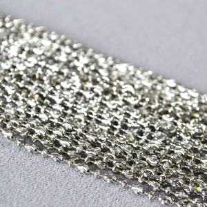 Macro detail of silver bead chain necklace featuring textured spiral oval metallic beads