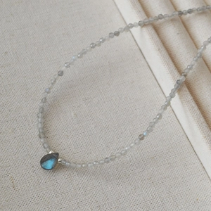 Macro shot of minimalist teardrop labradorite pendant with grey faceted bead chain
