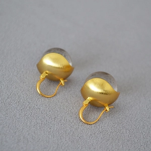 Macro view of gold brushed brass earrings with translucent grey crystal bead detail