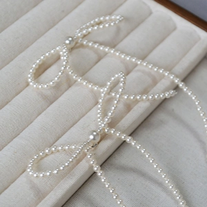 Handmade pearl bow tassel long earrings displayed in a minimalist white jewelry box
