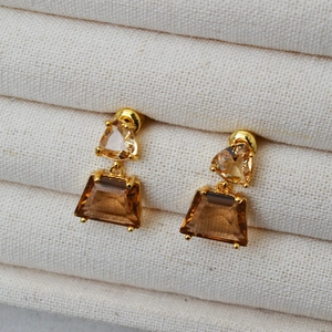 Detail of amber geometric earrings with triangular and trapezoidal facets in gold