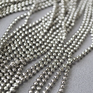 Close-up of diamond-cut ball chain texture in white gold plated copper metal
