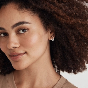 Minimalist irregular oval gold earrings with white enamel finish shown on a model