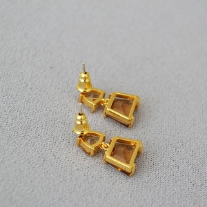 Detail of geometric triangle earrings with brown amber resin and gold metal base