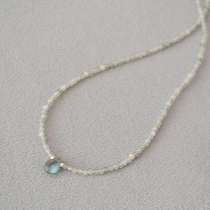 Macro shot of grey beaded necklace featuring a teardrop labradorite stone pendant