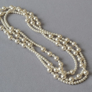 Detailed close-up of multi-layer faux pearl necklace with glossy iridescent finish