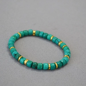 Detailed macro view of vintage turquoise barrel beads with golden metal spacers on elastic