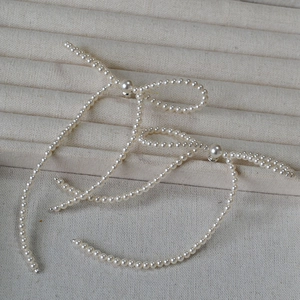 Detail of elegant hand-woven faux pearl bow earrings with long tassel in French style