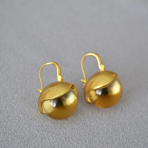 Detail view of gold brass drop earrings with clear crystal balls on grey fabric