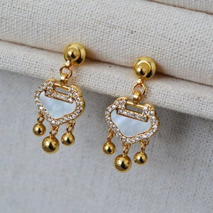 Detailed close-up of gold Ruyi lock earrings with white mother-of-pearl and beaded tassels