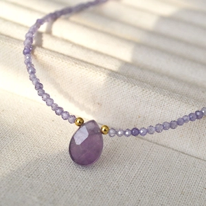 Macro shot of faceted pear-shaped amethyst pendant on a dainty beaded gemstone chain