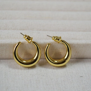 Detailed close-up of chunky gold C-shaped crescent earrings with mirror polished finish
