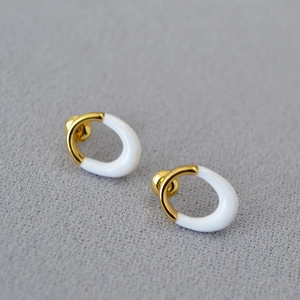 Detail of oval brass gold-plated earrings with white enamel and ball backings