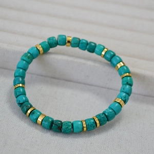 Macro detail of turquoise cylinder beads with gold spacers on an elastic bracelet