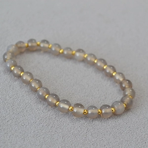 Close-up of translucent grey agate beads with gold spacers on a minimalist beaded bracelet