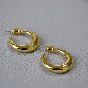 Detailed view of polished gold plated crescent hoop earrings with mirror finish and studs