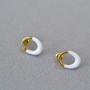 Detailed view of geometric gold-plated brass earrings with white enamel finish