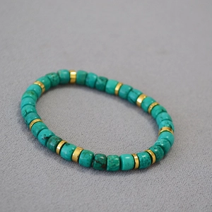 Detailed macro view of vintage turquoise cylinder beads and gold metal spacers on a bracelet