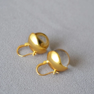 Macro shot of gold-plated brass bud earrings featuring clear crystal glass balls