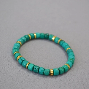 Macro shot of turquoise beads and golden spacer beads on a handmade stretch bracelet