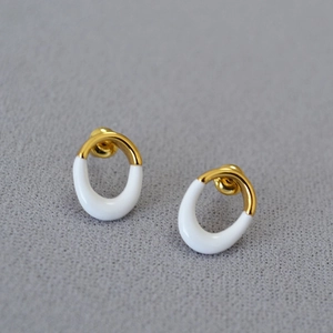 Detailed close-up of oval hoop earrings with gold plating and white enamel finish