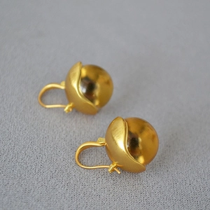 Close-up of vintage brushed gold earrings with amber glass bead drops and matte metal texture