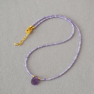 Detail of beaded purple amethyst necklace with a gold-plated teardrop gemstone pendant