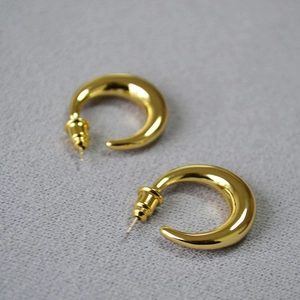 Detailed macro view of polished gold-plated crescent stud earrings with butterfly backs