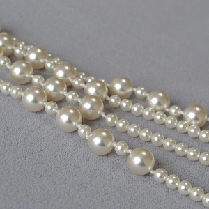 Detailed view of layered high-luster cream white pearls on textured grey fabric
