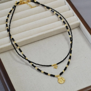 Vintage double layer black spinel necklace with sun coin and star charms on beige tray