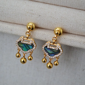 Macro view of gold Ruyi lock earrings with abalone shell inlay and white zircon accents