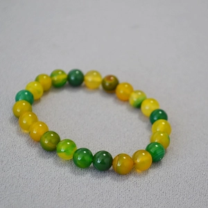 Detail of yellow and green agate beads with smooth polished finish on elastic bracelet