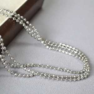 Detailed view of faceted silver beaded chain with reflective metallic diamond-cut finish