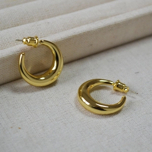 Detailed macro view of gold-plated crescent hoop earrings with high-polish mirror finish