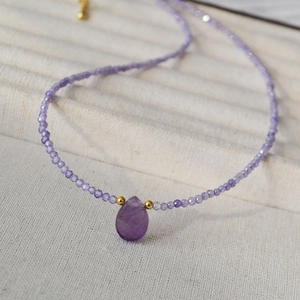 Macro detail of lavender beaded necklace featuring a purple teardrop gemstone pendant