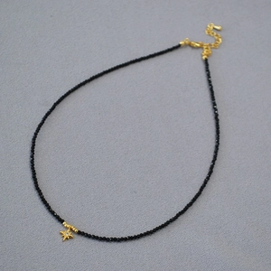 Close-up of black faceted beads necklace featuring a gold star pendant with zircon detail