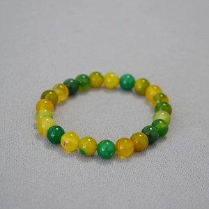 Handmade stretch bracelet with 8mm yellow and green agate beads on light textured background