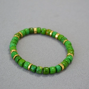 Macro detail of green turquoise beads and gold spacer discs on an elastic bracelet