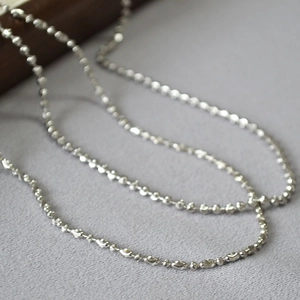 Close-up of diamond-cut bead chain in white gold plated copper with metallic luster