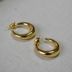 Detail view of thick gold crescent moon earrings on canvas background with focus on metal shine