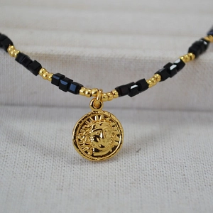 Detailed close-up of sun god medallion with black spinel and gold bead chain