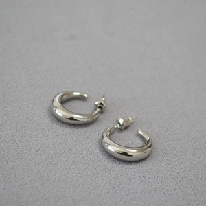 Detailed top view of chunky silver-toned metal hoop earrings on grey felt texture
