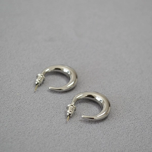 Macro shot of minimalist crescent-shaped silver studs with a polished mirror finish