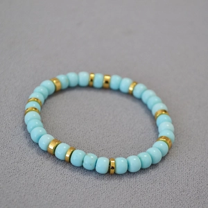 Minimalist turquoise beaded bracelet with gold flat spacers on a soft textured fabric